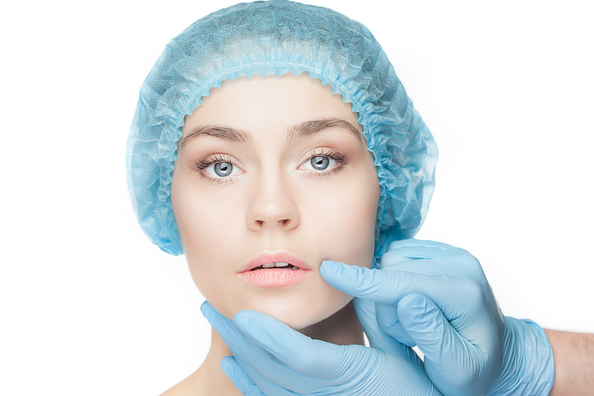 Plastic surgery concept. Doctor hands in gloves touching the beautiful woman face on white
